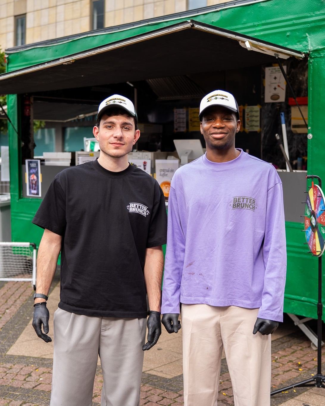 Die beiden Gründer von Better Brunch in Better-Brunch-Shirts vor ihrem grünen Foodtruck